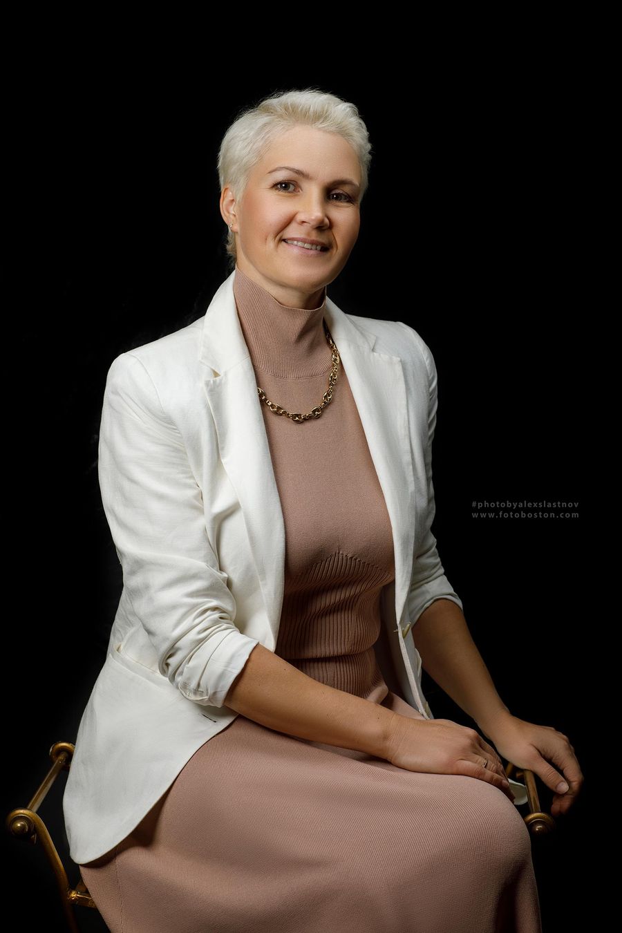 Business headshot of a woman in a white blazer on a black background, Boston headshot photographer
