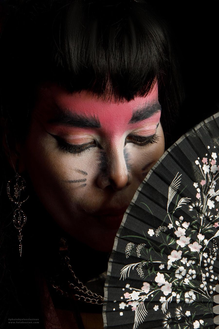 Creative portrait with stage makeup and a hand fan against a dark background