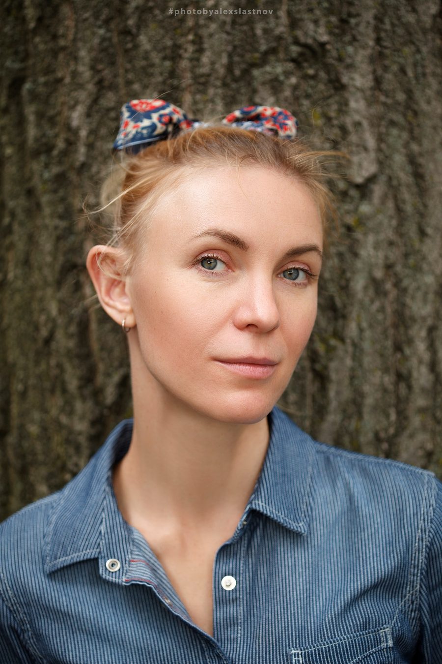 Natural light portrait of a woman in a blue corduroy shirt against tree bark