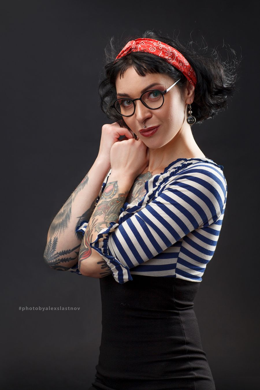 Studio portrait of a woman in a red bandana and a striped top on a dark grey background
