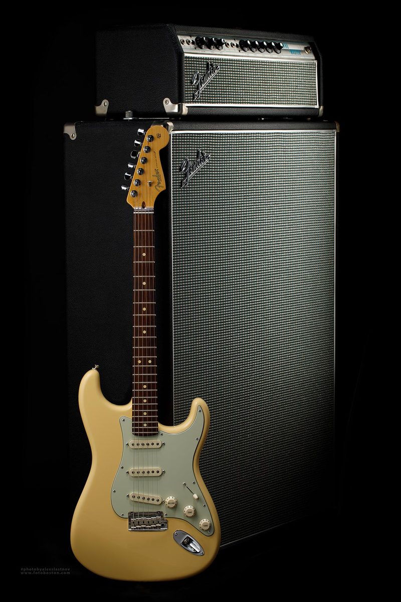 Electric guitar in front of an amplifier stack on a black background, studio product photography